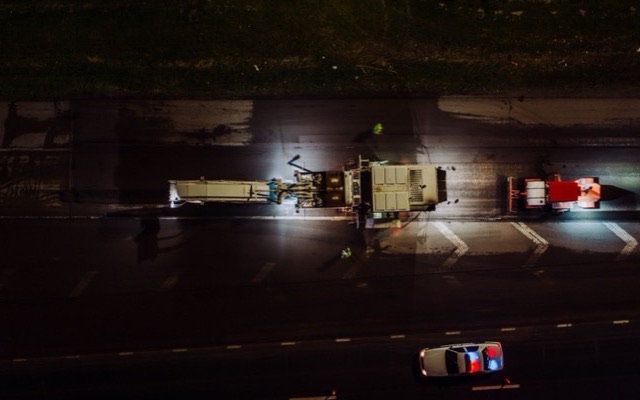 Night road work lit on a highway, seen from above