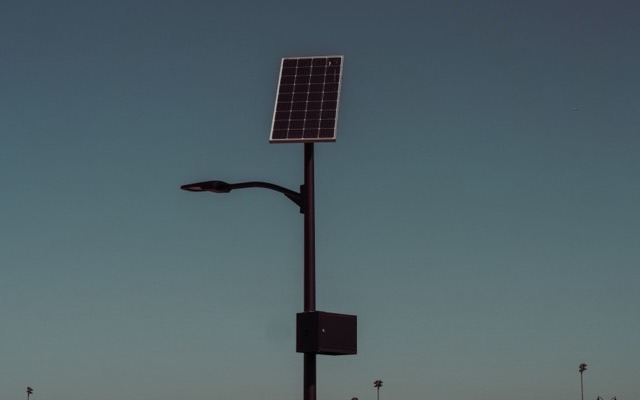 Solar street light with its panel above the fixture at dusk